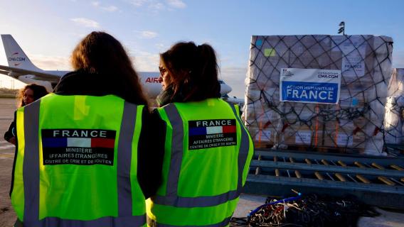 Photo de l'envoi aide humanitaire Liban CDCS fondation CMA CGM avec deux personnes de dos portant le dossard Ambassade française